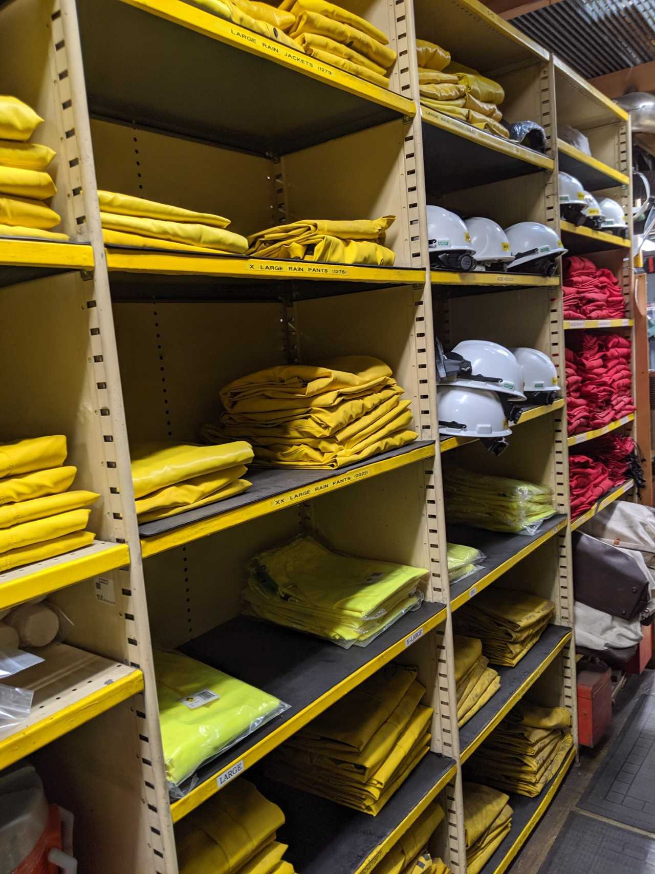 Contents of 5x sections shelving - rain jackets, hard hats, face shields, water coolers, acid bibs - SAFETY SWITCH Contents of 5x sections shelving - rain jackets, hard hats, face shields, water coolers, acid bibs - SAFETY SWITCH